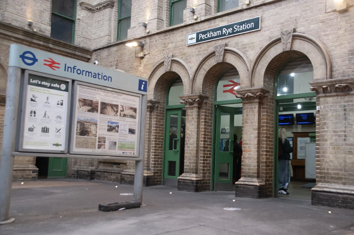 The arched brick entrance to Peckham Rye station, with a Network Rail information board about the station improvements in the forecourt